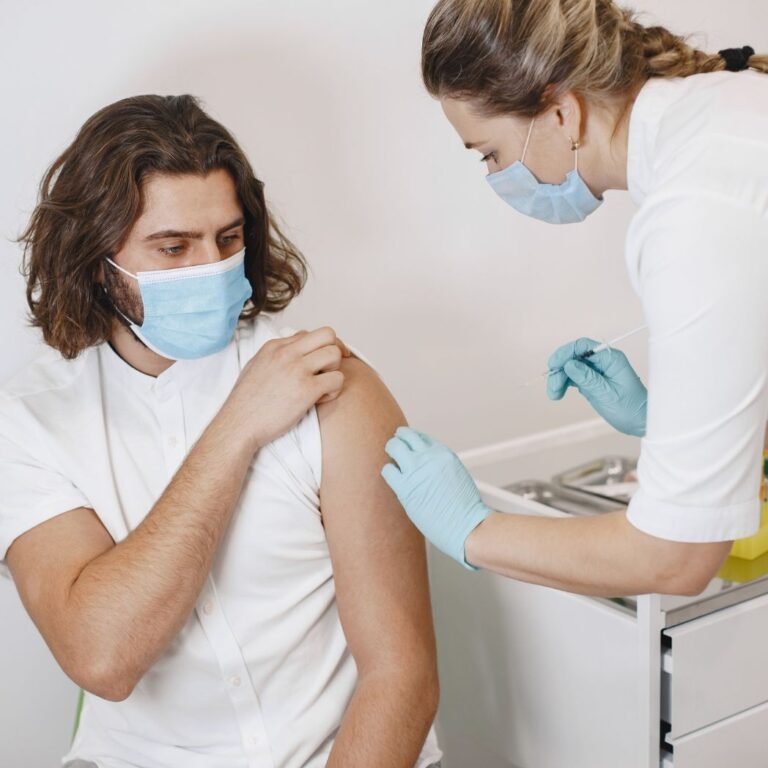 Immune dysregulation treatment consultation with healthcare professional administering injection to patient wearing mask.