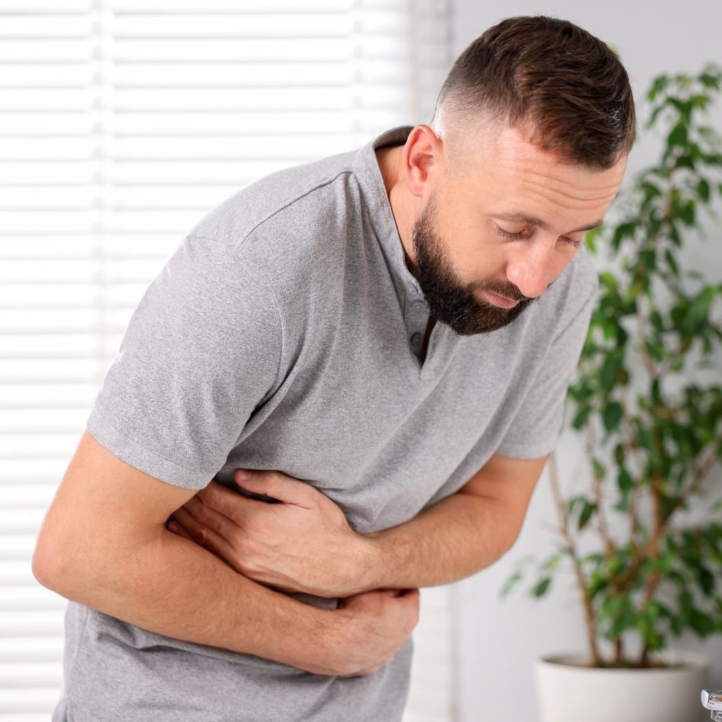 Man experiencing digestive discomfort and stomach pain symptoms linked to immune dysregulation issues.