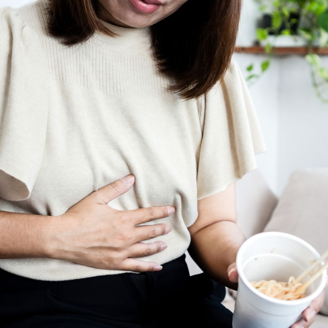 The women in the image show the pain of her Bloating and Digestive Distress in stomach