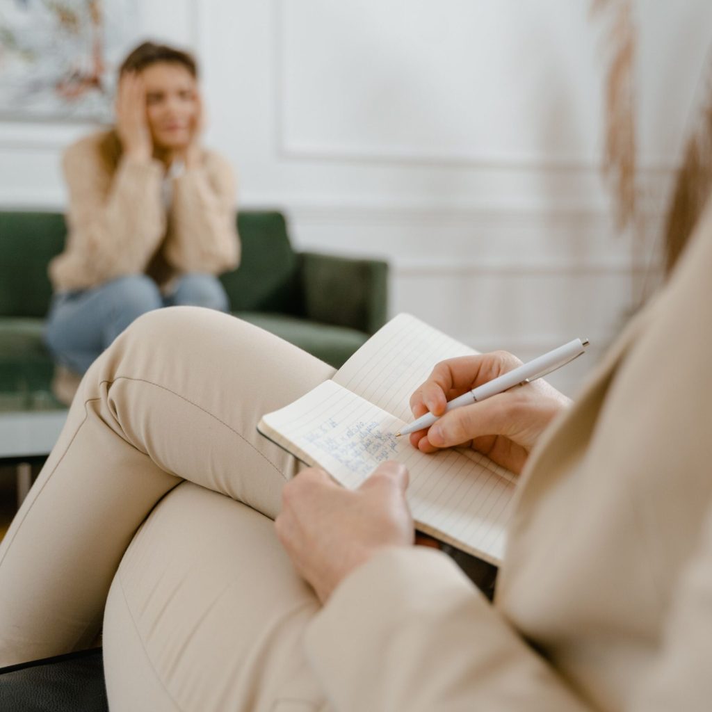 Mental health counseling session with therapist taking notes for emotional wellness support